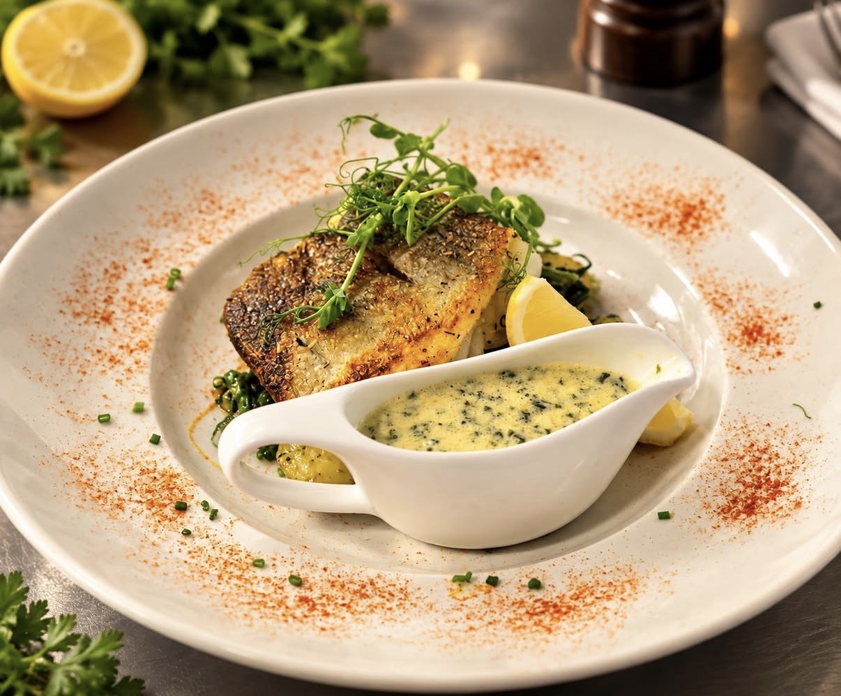 Pan-fried sea bass served with a jug of sauce